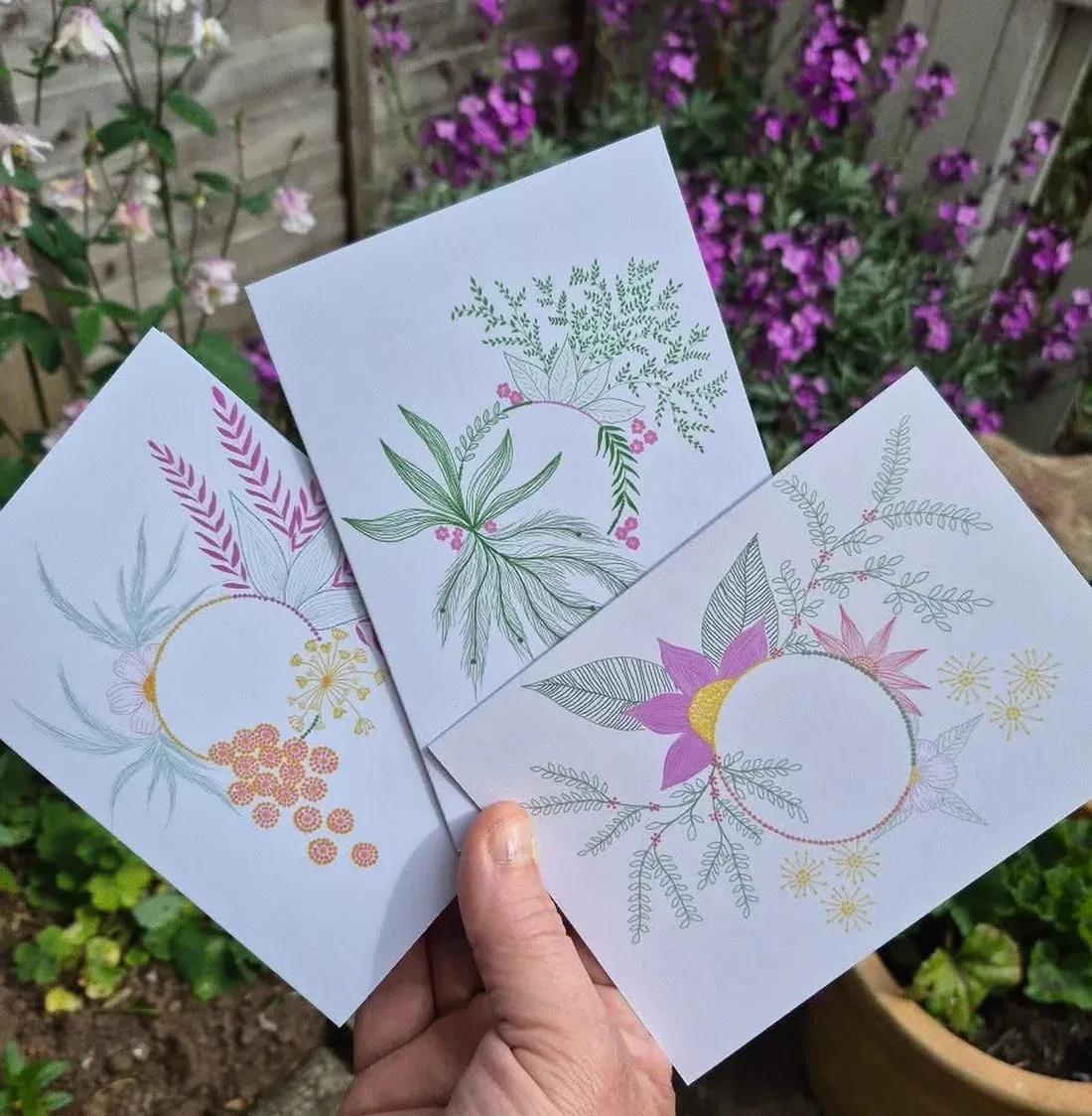Beka holding three of her botanical cards in her garden